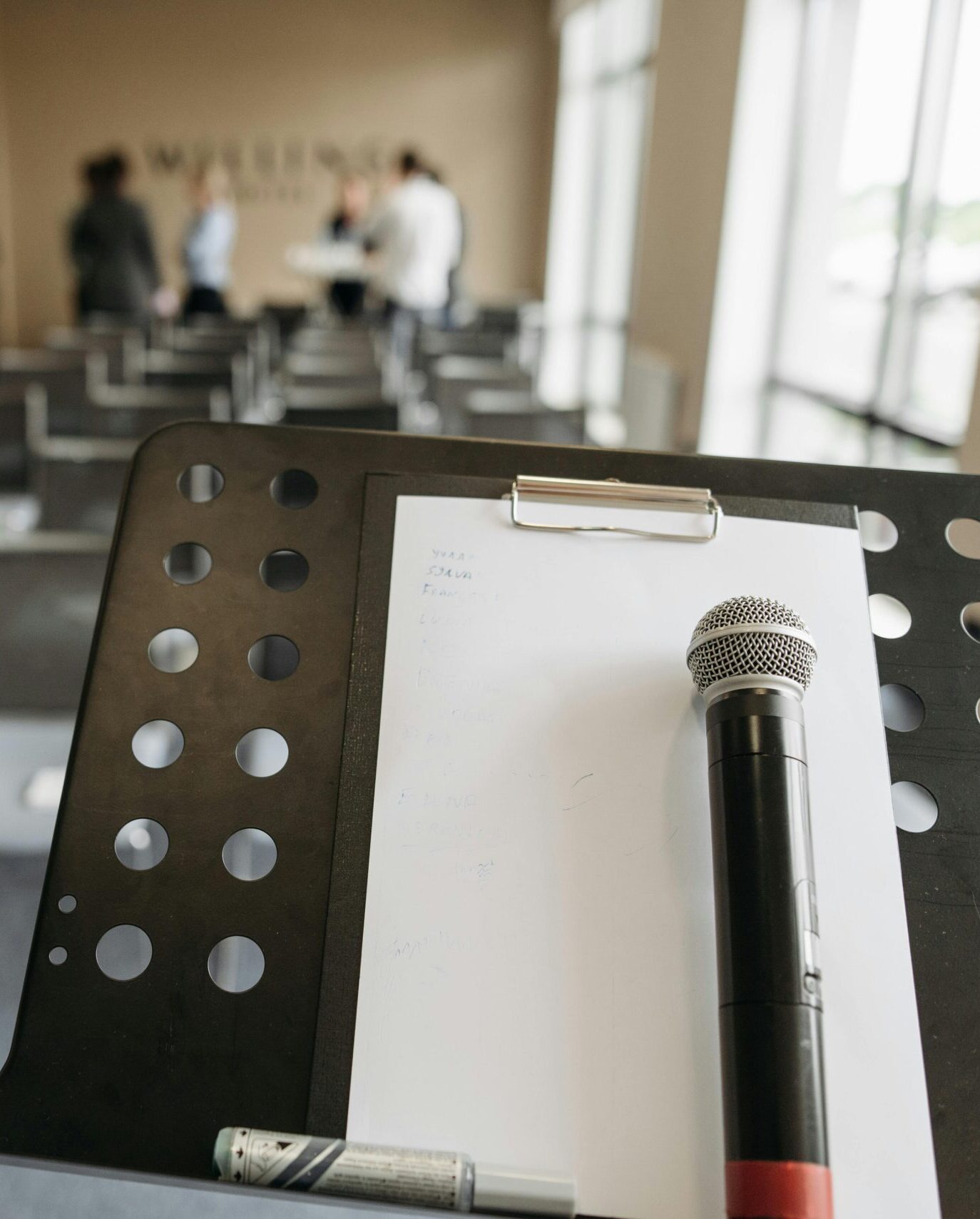 Close-up of a microphone on a stand in a conference room setting.